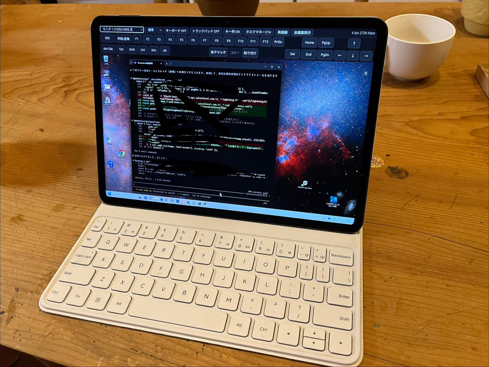 木のテーブルに置いたタブレットと薄型キーボード。画面いっぱいに、離れた場所にある Windows PC のデスクトップがブラウザで表示され、上部にモニタ選択・画質と、ESC・F1〜F12・矢印・修飾キー・右クリック・コピー・貼り付けのキー列が並んでいる。